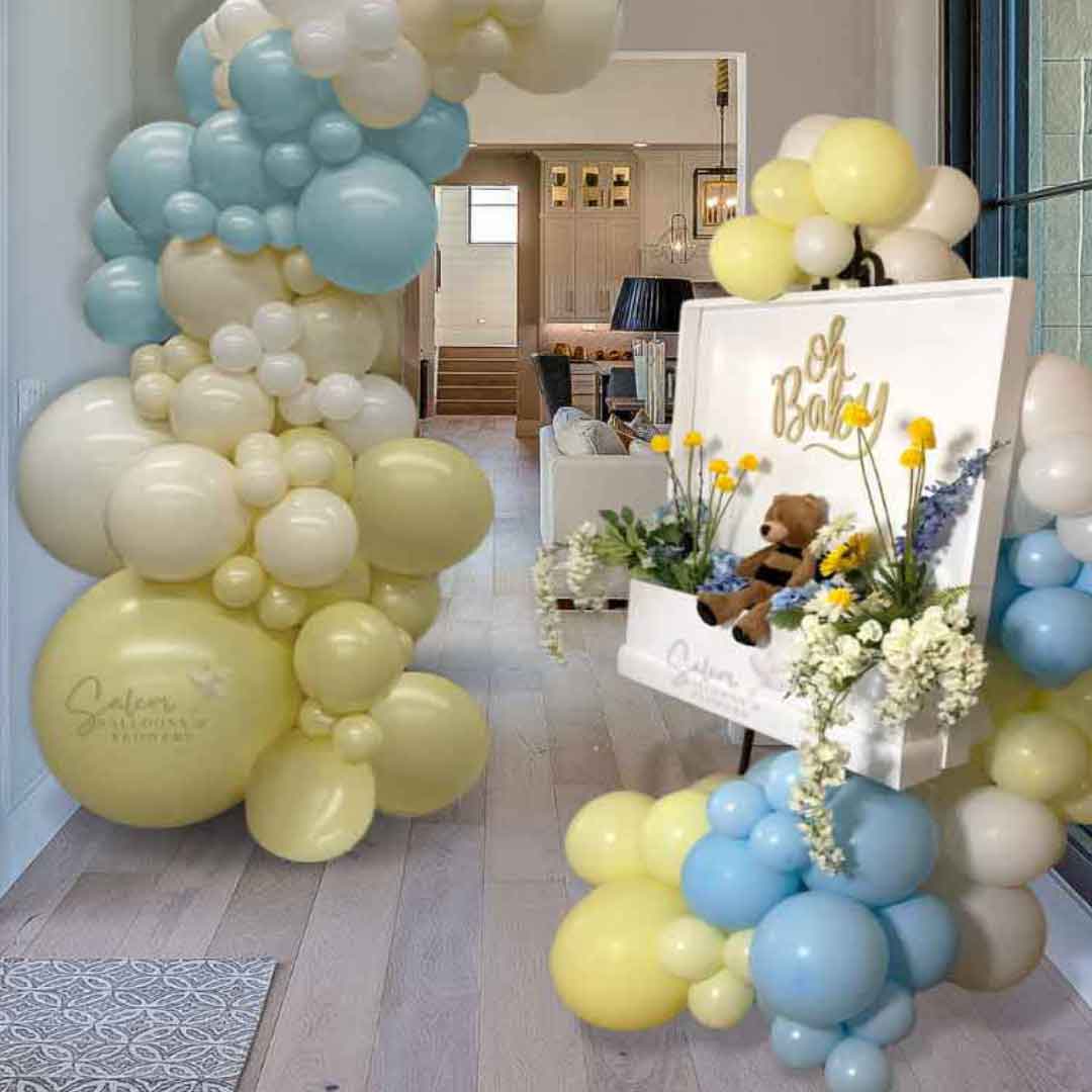 Flower Box Welcome Sign filled with blue and yellow flowers and an adorable plush sitting on a bronze easel and decorated with balloon garland. Salem Oregon balloon decor.